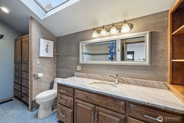 a bathroom with a granite countertop sink a toilet and a mirror