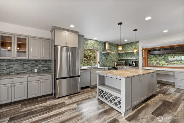 a kitchen with stainless steel appliances granite countertop a stove a refrigerator a sink and a oven with wooden floor