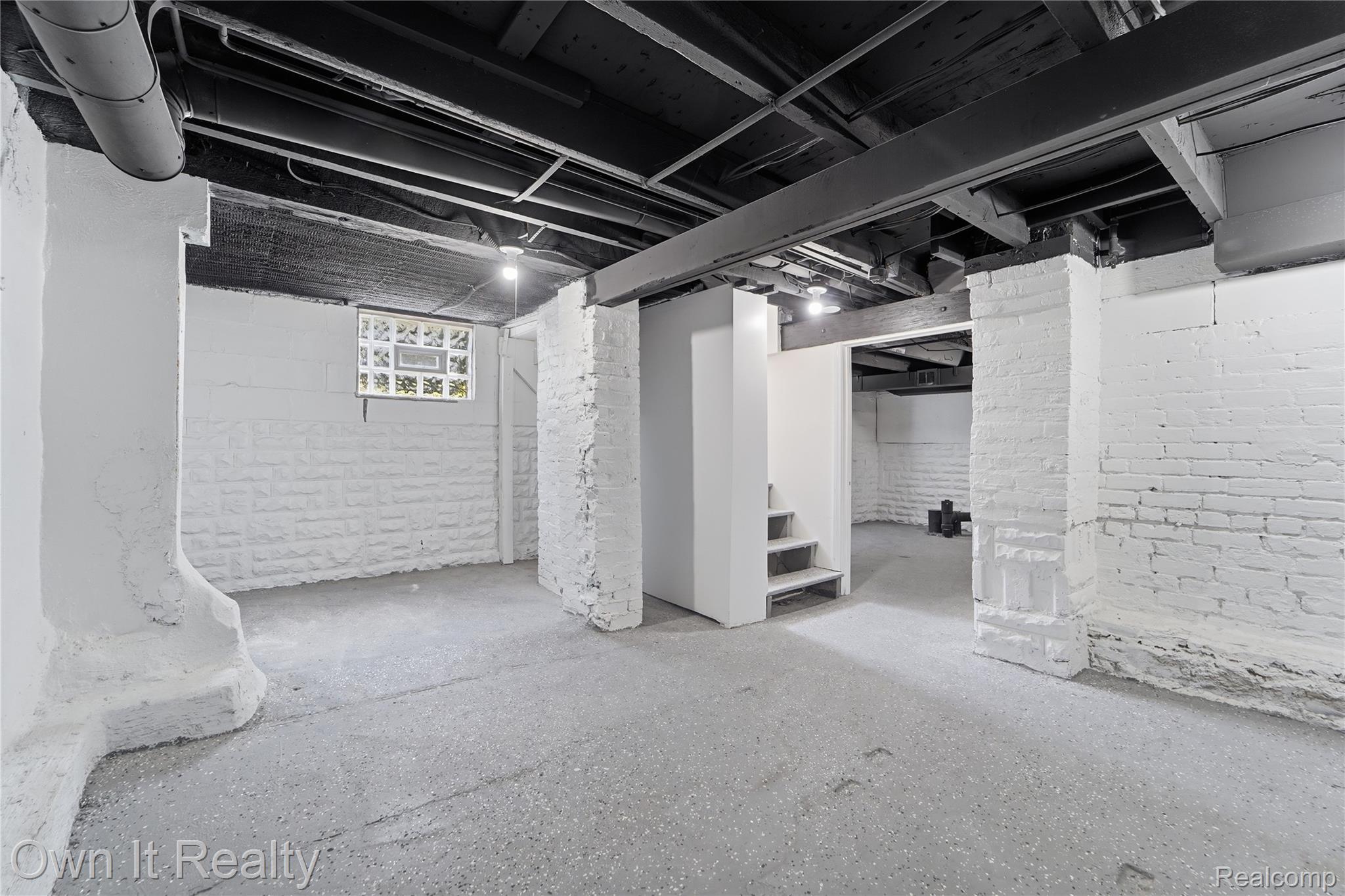 168 Kerby Road Grosse Pointe, MI 48236 - Photo 31 of 36 Concrete flooring, exposed ceiling beams, painted brick walls, glass block window, and functional staircase