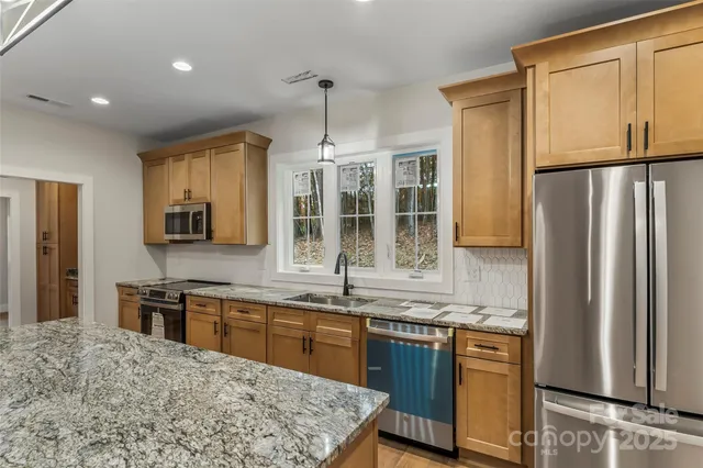 a kitchen with stainless steel appliances granite countertop a refrigerator a sink dishwasher a stove with wooden cabinets and floor