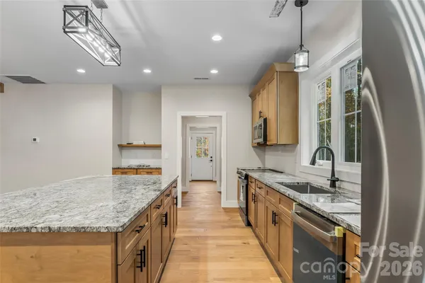 a large kitchen with kitchen island granite countertop a sink and a stove