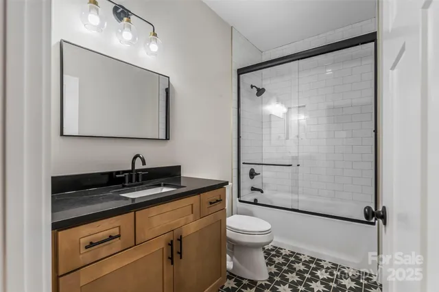a bathroom with a granite countertop sink toilet a mirror a vanity and shower