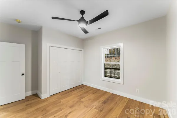 a view of empty room with wooden floor and ceiling fan