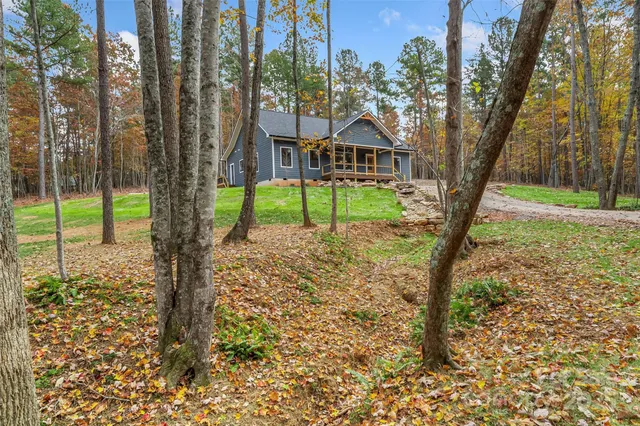a view of a yard in front of a house with large trees