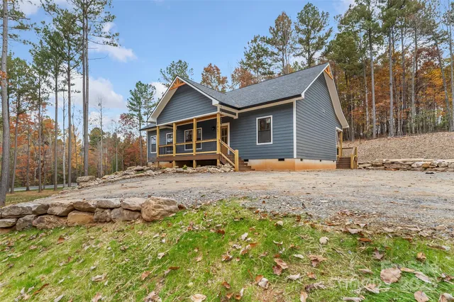 a view of a house with large trees and wooden fence