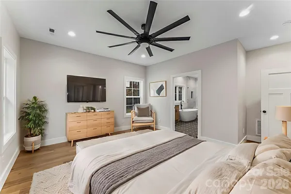 a bedroom with a large bed and a flat tv screen on dresser