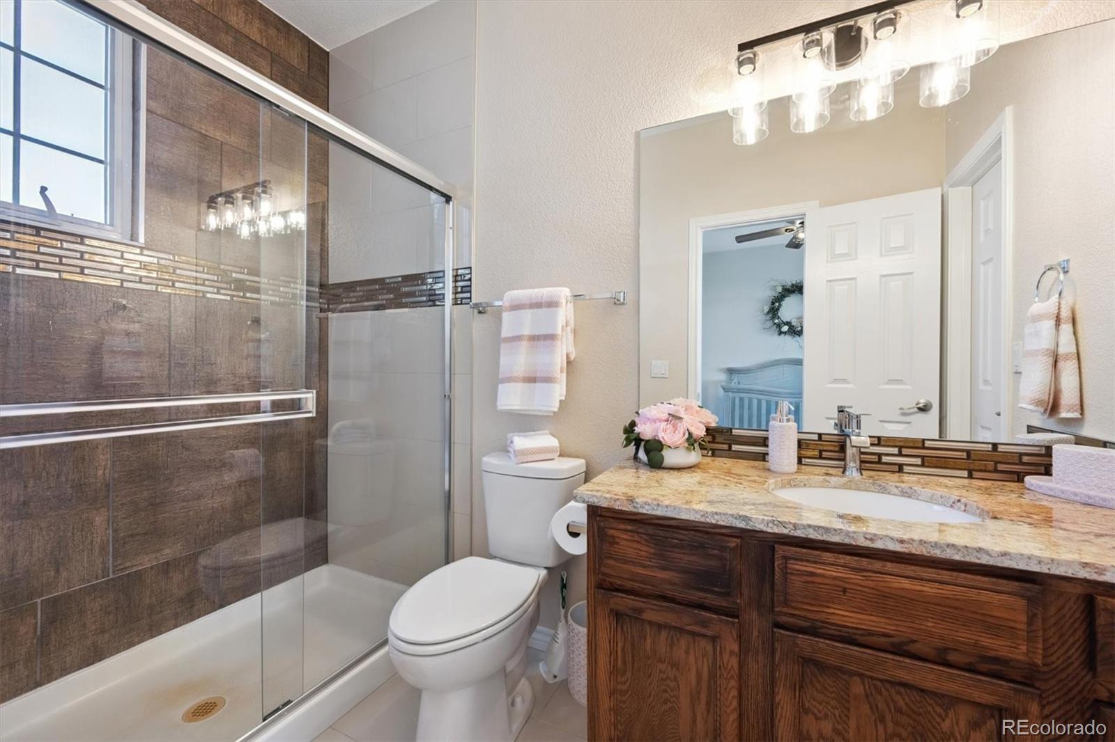 724 Imboden Road Watkins, CO 80137 - Photo 25 of 50 a bathroom with a granite countertop sink toilet and shower