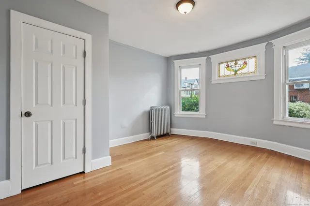 an empty room with wooden floor and windows