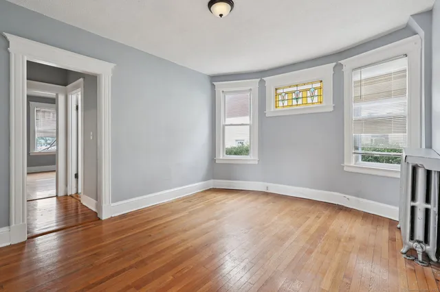 an empty room with wooden floor and windows