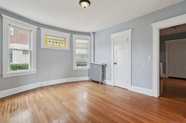 a view of an empty room with wooden floor and closet