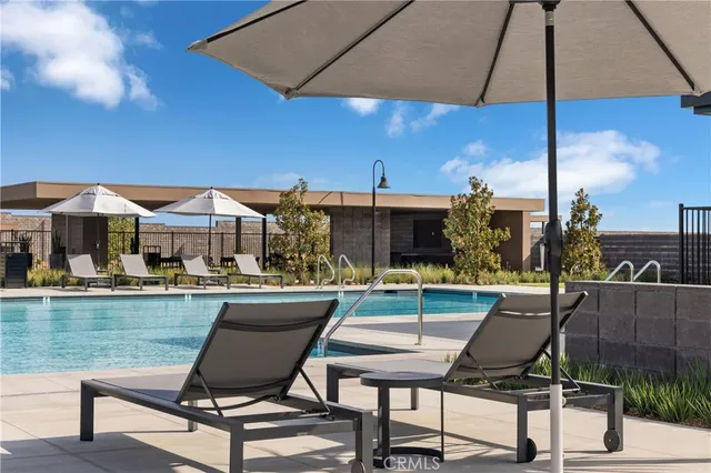 a view of a swimming pool with lawn chairs under an umbrella