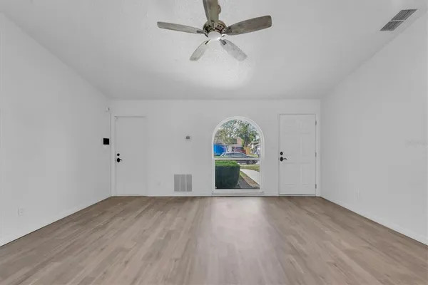 an empty room with wooden floor and ceiling fan