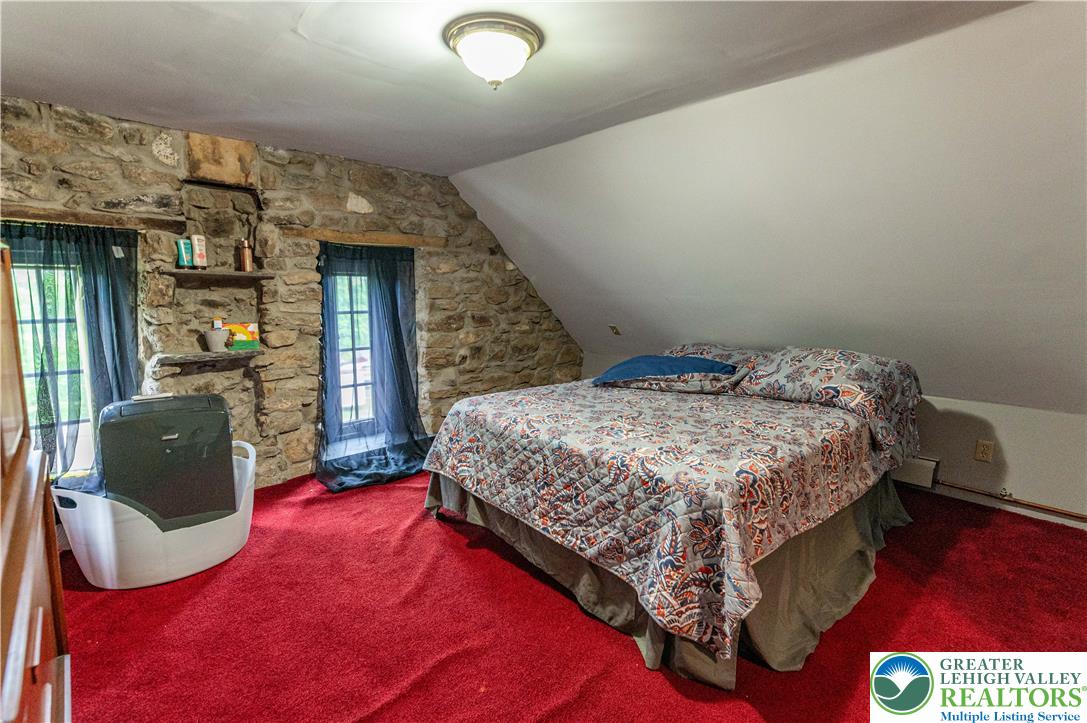 2485 Hieter Road Quakertown, PA 18951 - Photo 53 of 97 Exposed stone walls and a sloped ceiling define this cozy bedroom with vibrant carpeting.