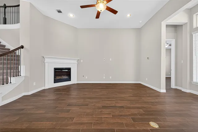 an empty room with wooden floor fireplace and window