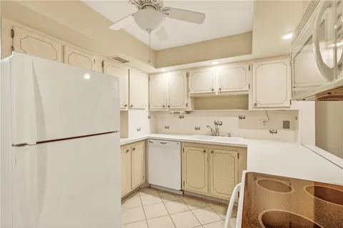 a kitchen with a sink a stove a refrigerator and white cabinets with wooden floor