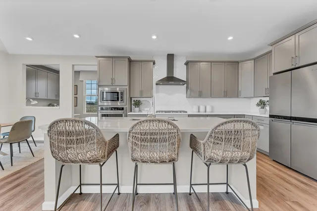 a kitchen with stainless steel appliances granite countertop a table chairs and a refrigerator