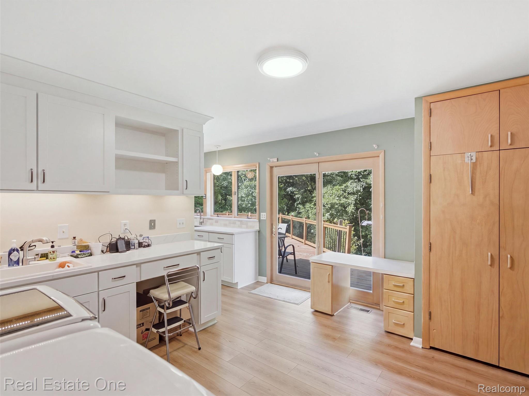 2626 West Wattles Road Troy, MI 48098 - Photo 21 of 65 White cabinetry with integrated sink, light wood-finish flooring, sliding glass doors to exterior, built-in desk area, and full-height wood-finish storage