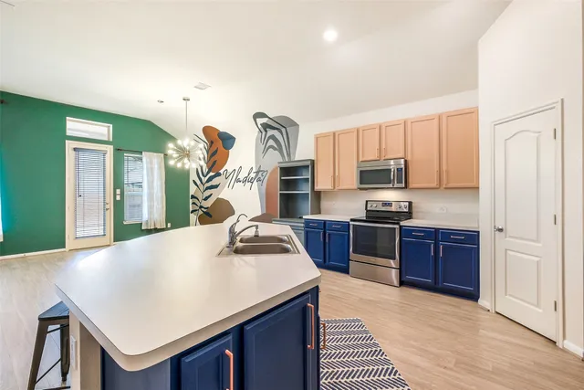 a kitchen with a stove a sink dishwasher and a refrigerator with wooden floor