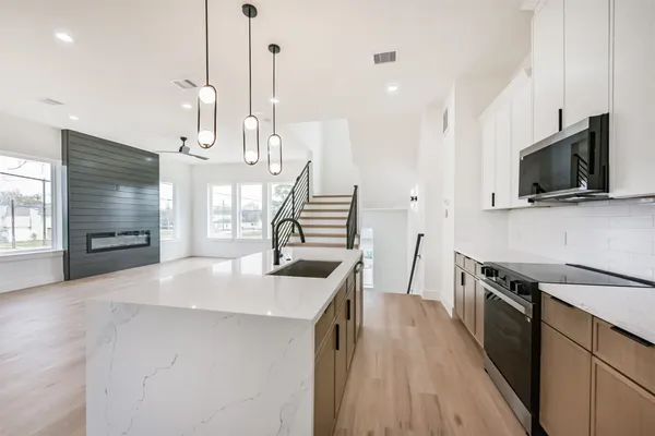 a kitchen with stainless steel appliances granite countertop a sink a stove and a wooden floor
