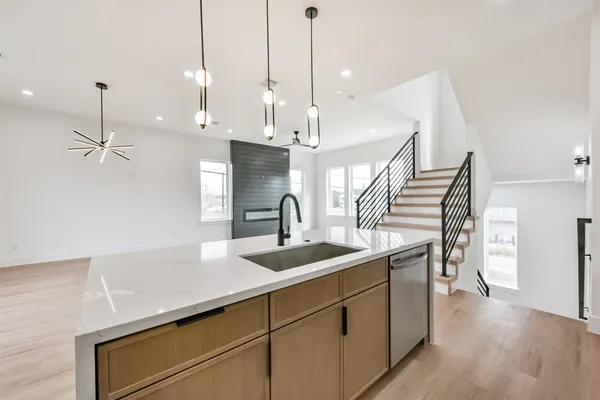 a kitchen with stainless steel appliances granite countertop a sink a stove and a wooden floor