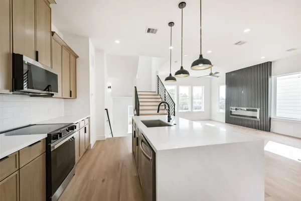 a kitchen with stainless steel appliances granite countertop a sink a stove and a wooden floor