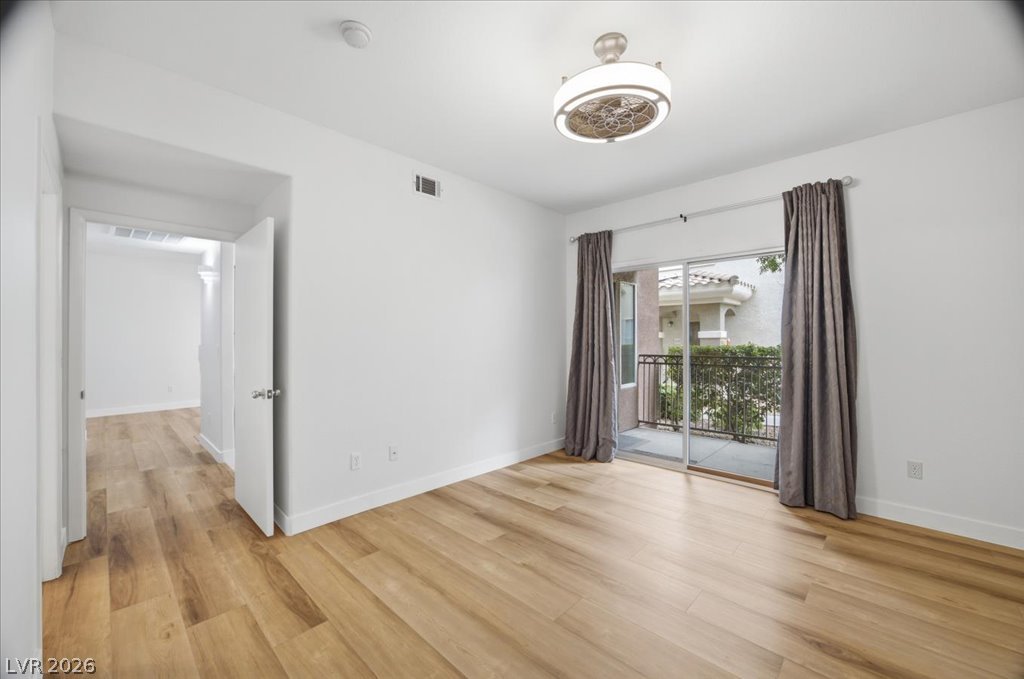 9050 West Warm Springs Road, Unit 1033 Las Vegas, NV 89148 - Photo 8 of 26 Hardwood floors and a private balcony define this naturally lit bedroom, offering comfort and outdoor access.