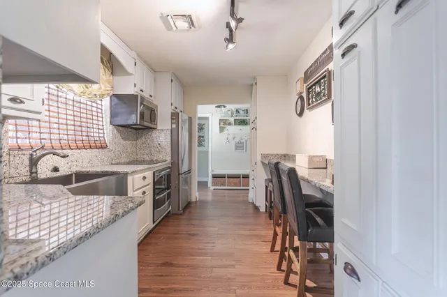 a kitchen with granite countertop cabinets stainless steel appliances and a dining table