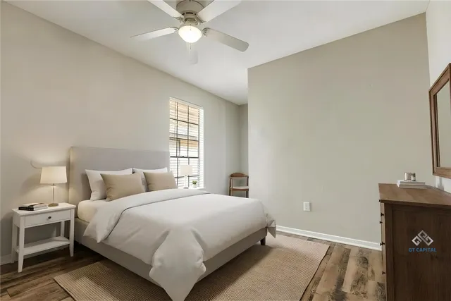 an empty room with wooden floor fan and windows