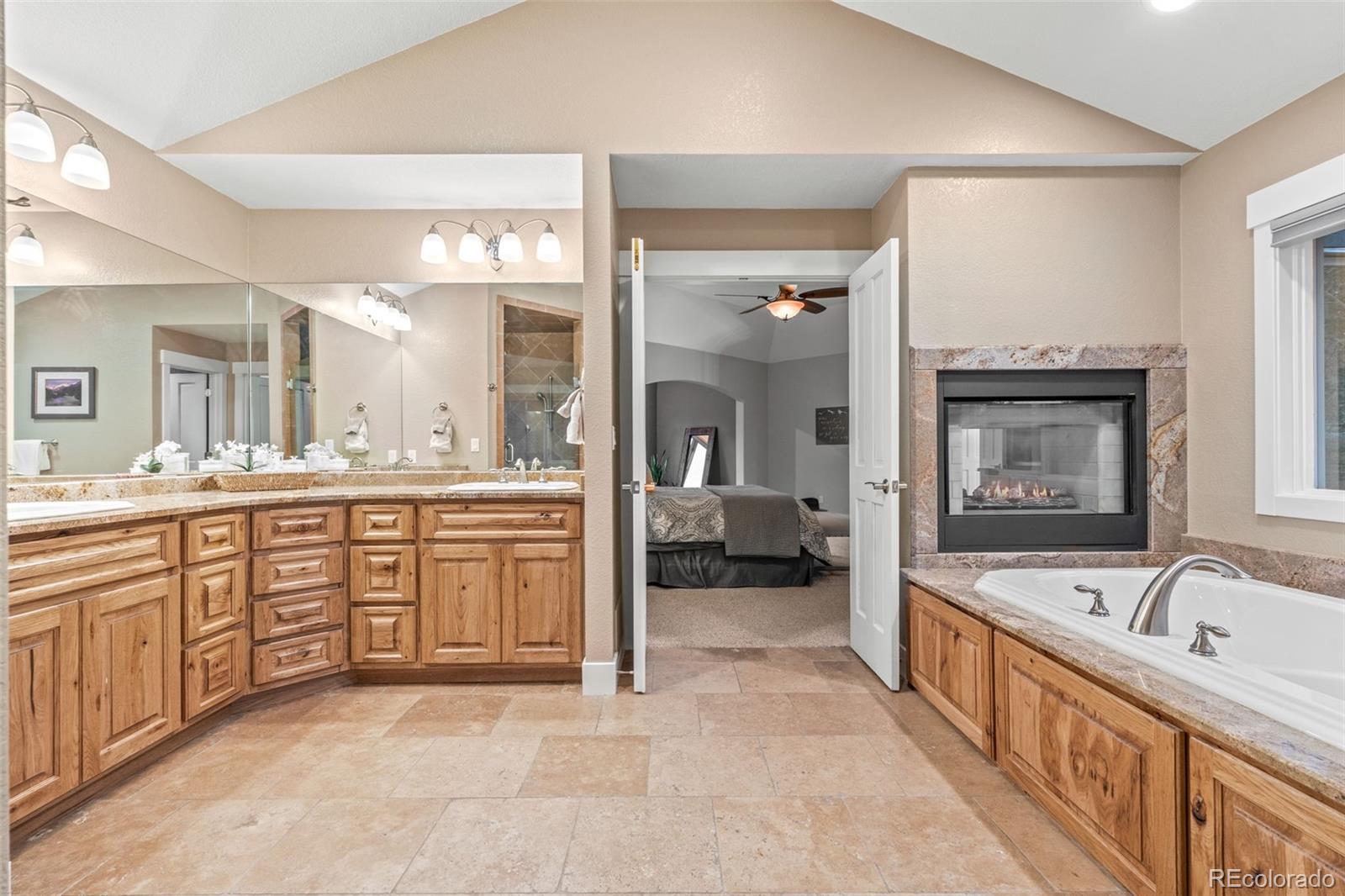 1735 Prima Lane Evergreen, CO 80439 - Photo 28 of 50 a large en suite bathroom with a granite countertop double vanity sink a mirror a bathtub and next to a window