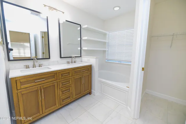 a bathroom with a double vanity sink a mirror and a bathtub