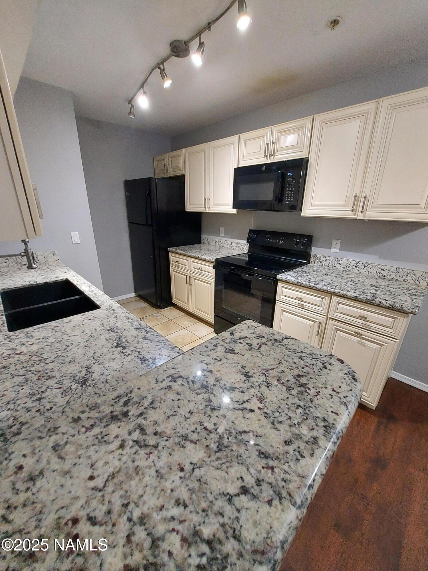 1385 West University Avenue, Unit 11181 Flagstaff, AZ 86001 - Photo 3 of 8 a kitchen with stainless steel appliances kitchen island granite countertop a stove a sink and a microwave