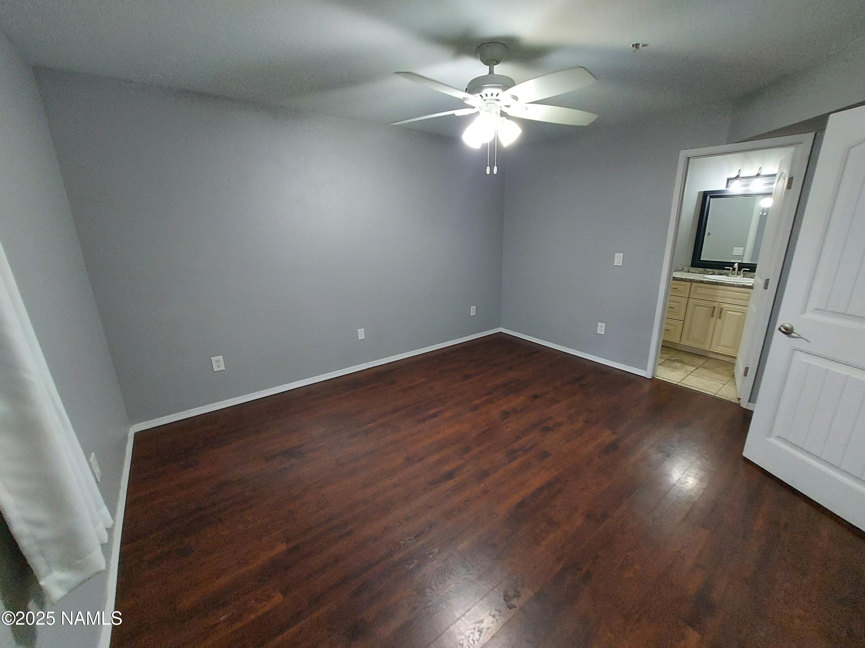 1385 West University Avenue, Unit 11181 Flagstaff, AZ 86001 - Photo 6 of 8 an empty room with wooden floor and fan