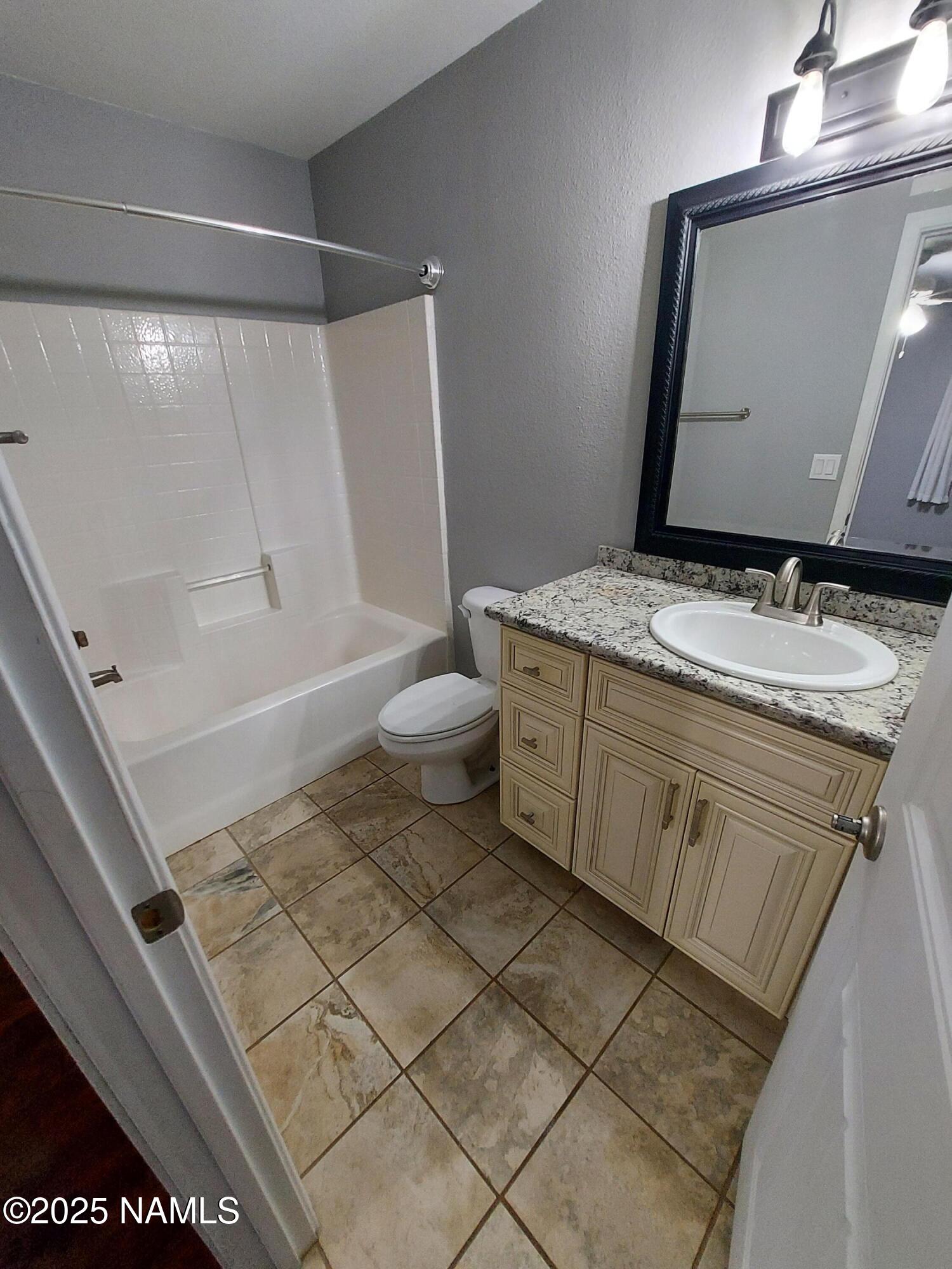 1385 West University Avenue, Unit 11181 Flagstaff, AZ 86001 - Photo 7 of 8 a bathroom with a granite countertop sink toilet and shower