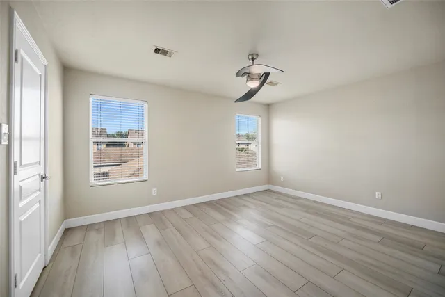 a view of empty room with wooden floor and fan