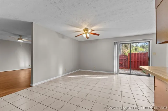 a view of an empty room and window and a chandelier fan
