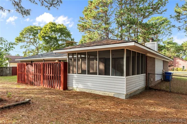 a view of wooden house with a small yard and large trees