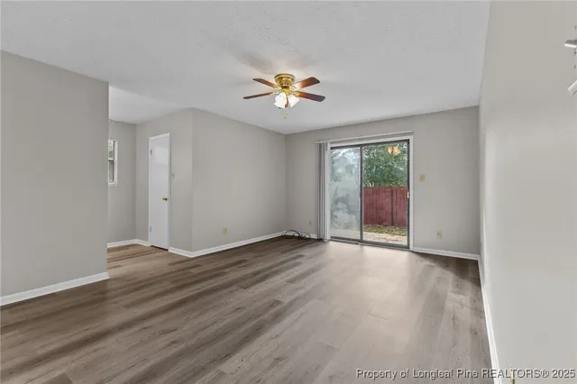 an empty room with wooden floor and fan