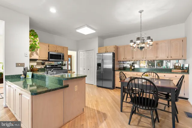a kitchen with stainless steel appliances granite countertop a dining table chairs and granite counter tops
