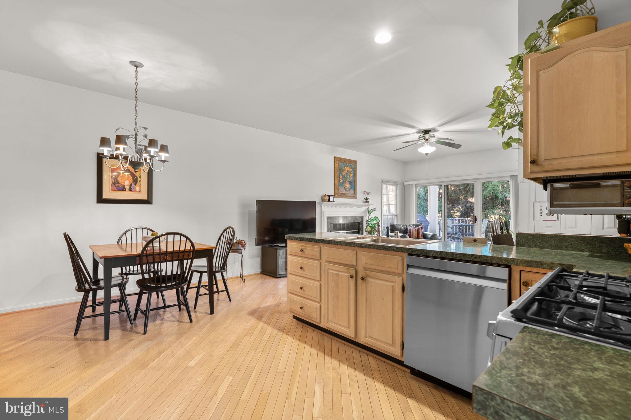 5161 Harpers Farm Road, Unit 27 Columbia, MD 21044 - Photo 16 of 55 a kitchen with stainless steel appliances granite countertop a stove top oven a sink a dining table and chairs with wooden floor