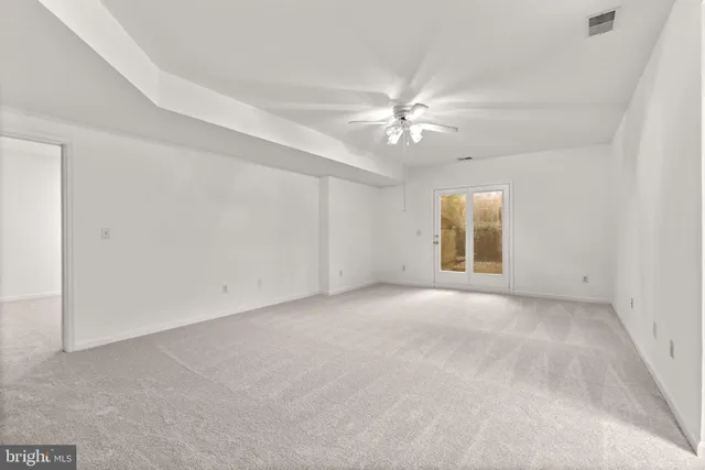an empty room with a ceiling fan and windows