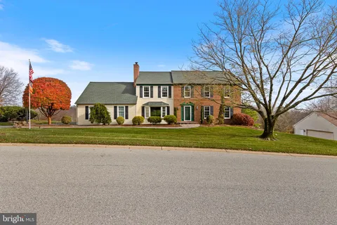 a view of house with a big yard and large trees