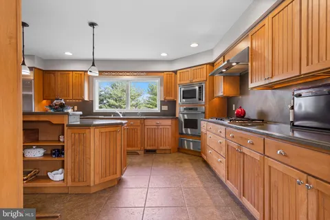 a kitchen with stainless steel appliances kitchen island granite countertop a refrigerator and microwave