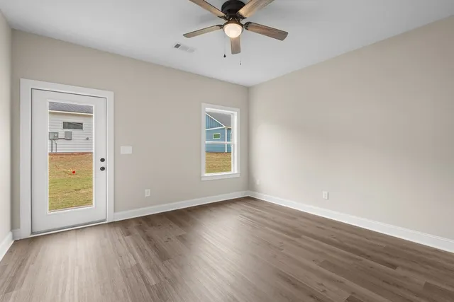 an empty room with wooden floor and windows