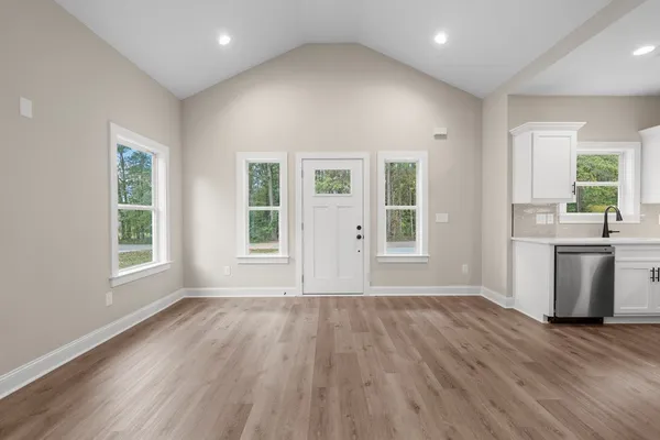 an empty room with wooden floor and windows