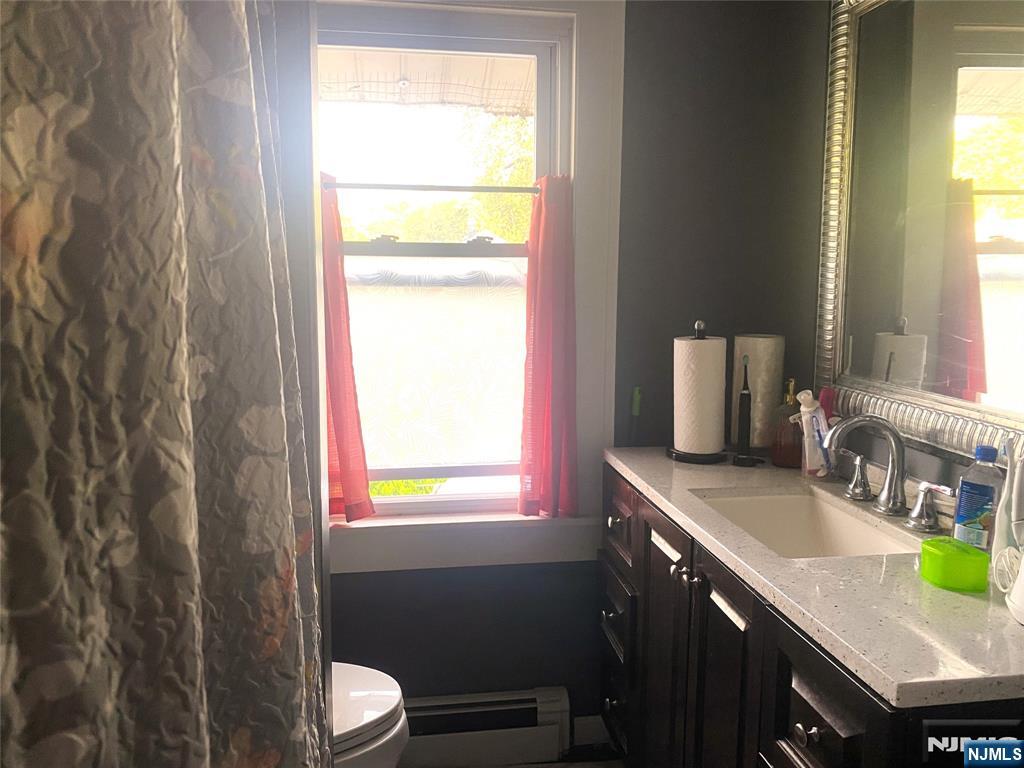 857 Garrison Avenue Teaneck, NJ 07666 - Photo 5 of 5 a bathroom with a granite countertop sink toilet and mirror