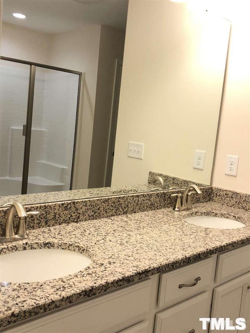2555 Rambling Creek Road Apex, NC 27523 - Photo 12 of 23 a view of a granite countertop sink and a mirror