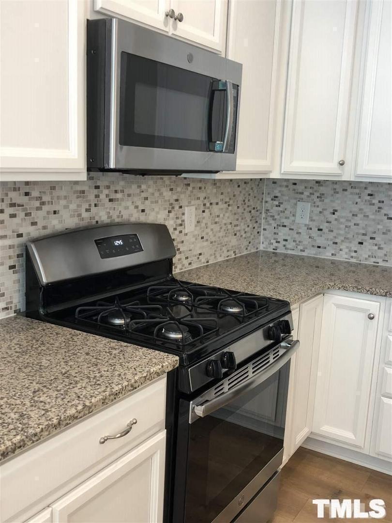 2555 Rambling Creek Road Apex, NC 27523 - Photo 5 of 23 a kitchen with granite countertop white cabinets and appliances