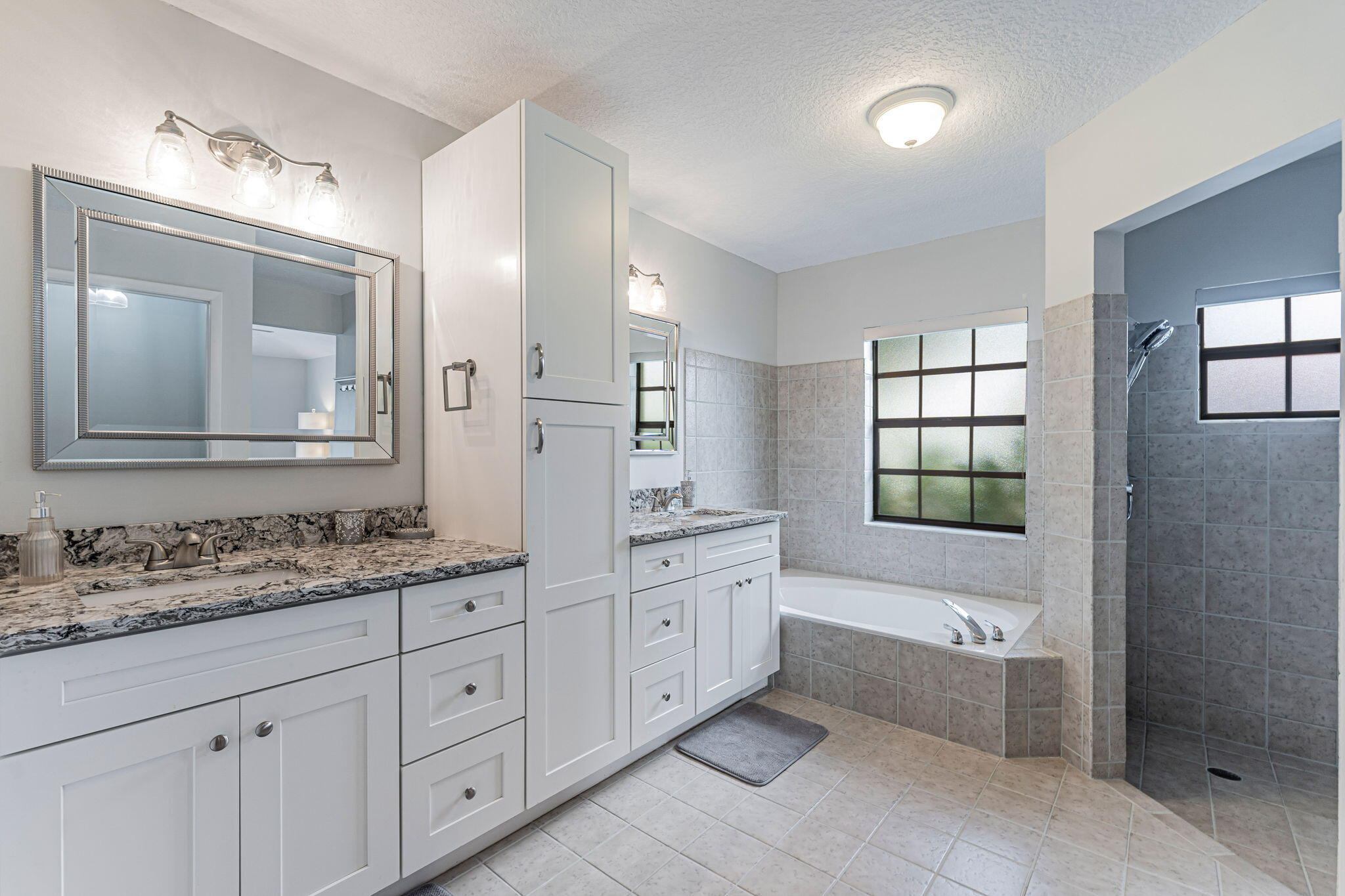 12715 Kingsway Road Wellington, FL 33414 - Photo 20 of 36 a bathroom with a granite countertop double vanity sink a mirror bathtub and next to a window
