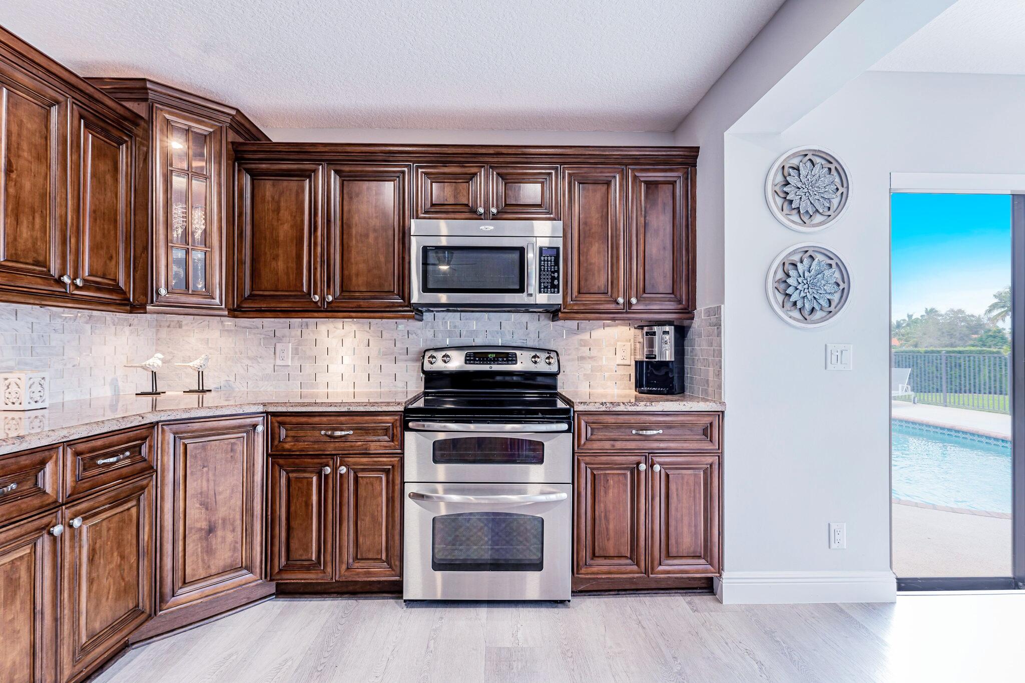 12715 Kingsway Road Wellington, FL 33414 - Photo 10 of 36 a kitchen with granite countertop a stove top oven microwave and cabinets