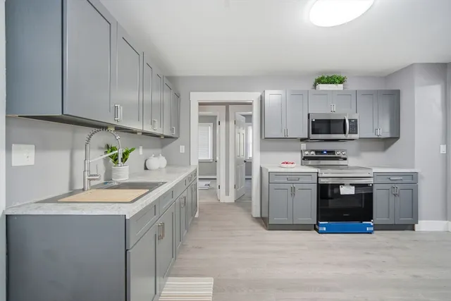 a kitchen with granite countertop a sink stainless steel appliances and white cabinets